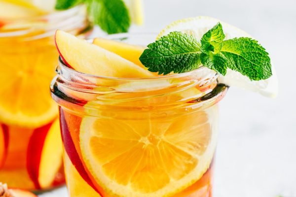 Cold peach and lemon iced tea. Summer refreshing drink with peach, lemon and ice.