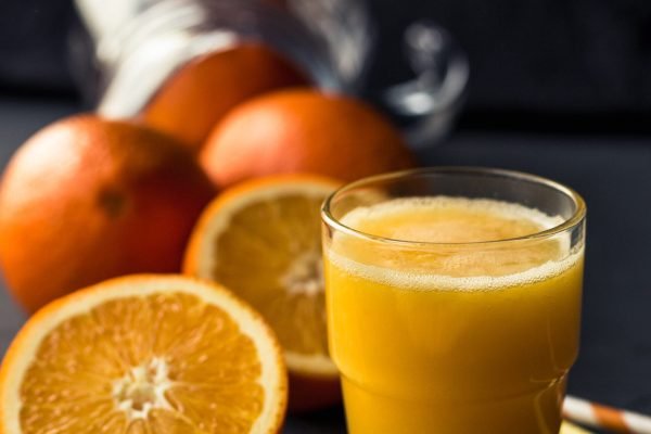 Fresh orange juice and fresh fruit oranges on a black background