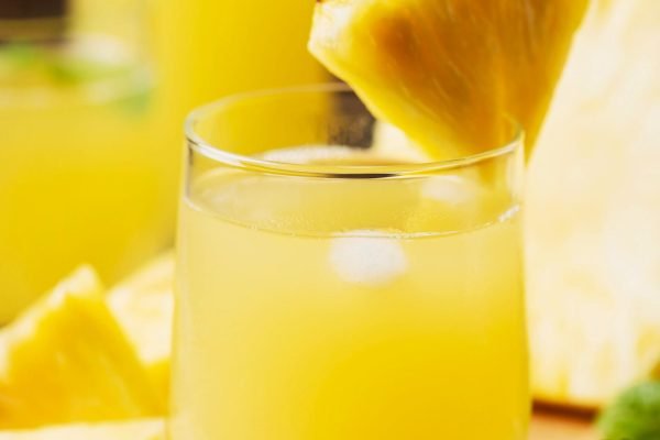 Fresh summer pineapple juice on the rustic wooden table, selective focus image