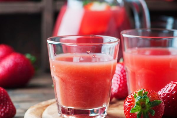 Sweet strawberry juice on the wooden table, selective focus and square image